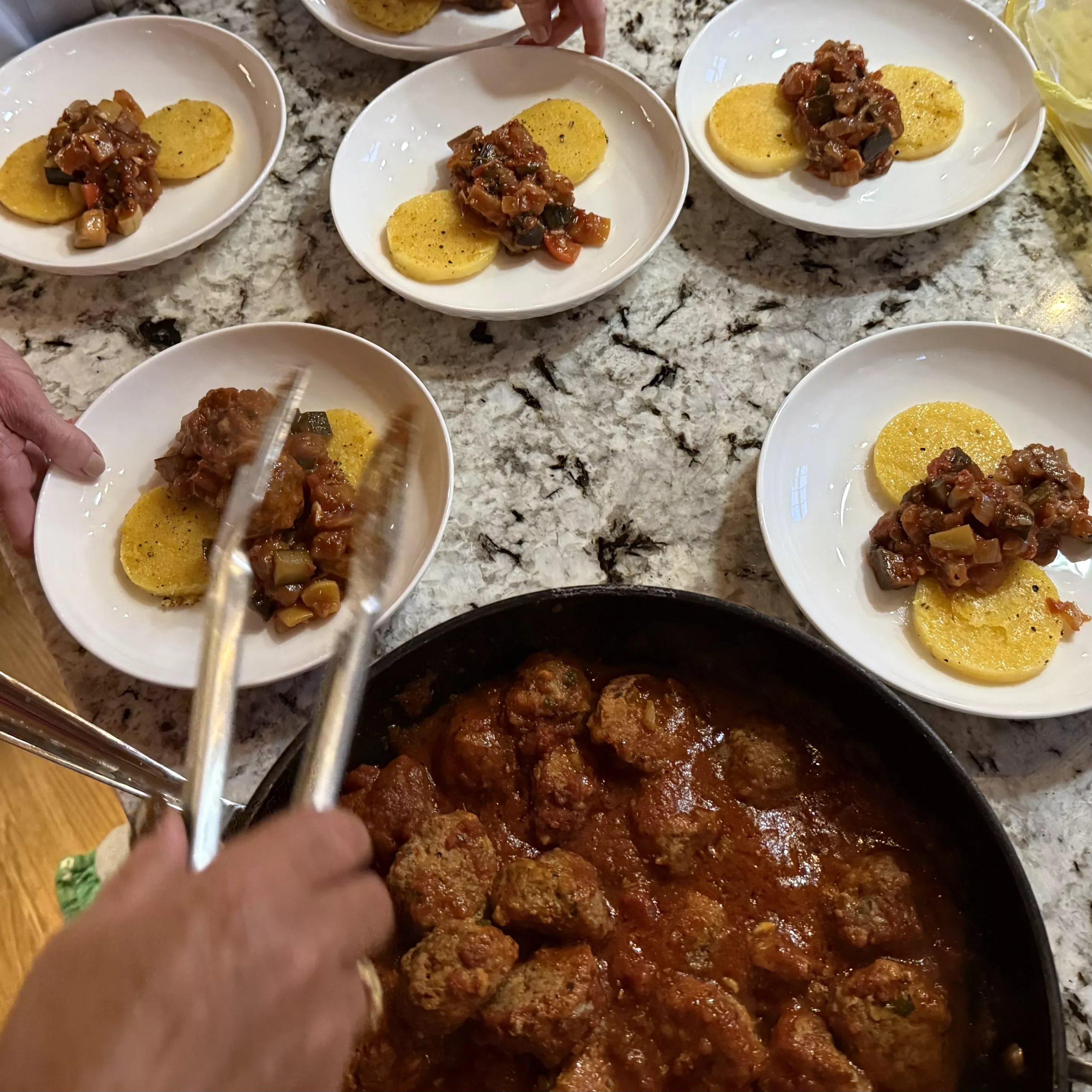 Placing meatballs onto ratatouille