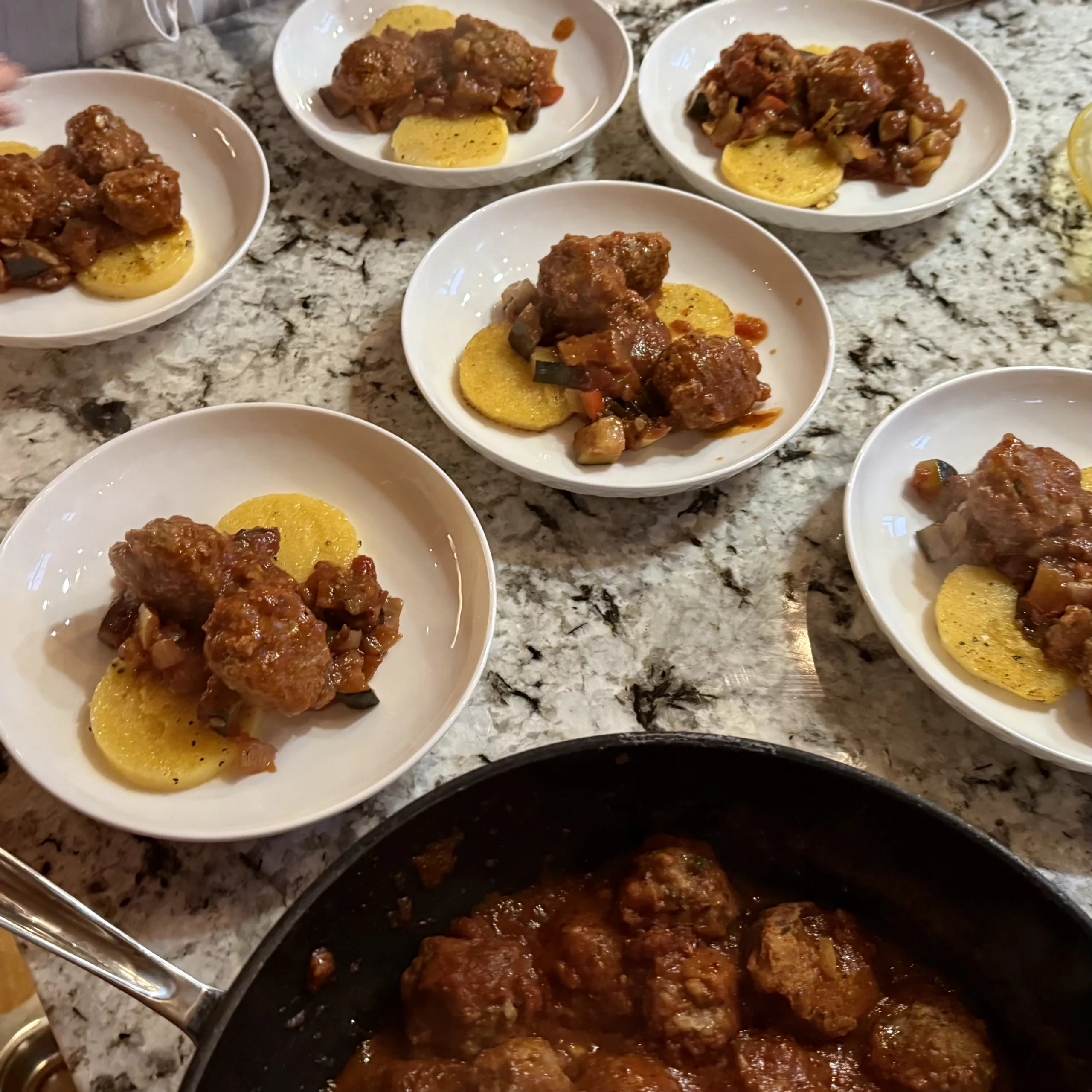 Plated meatballs over ratatouille with a polenta cake