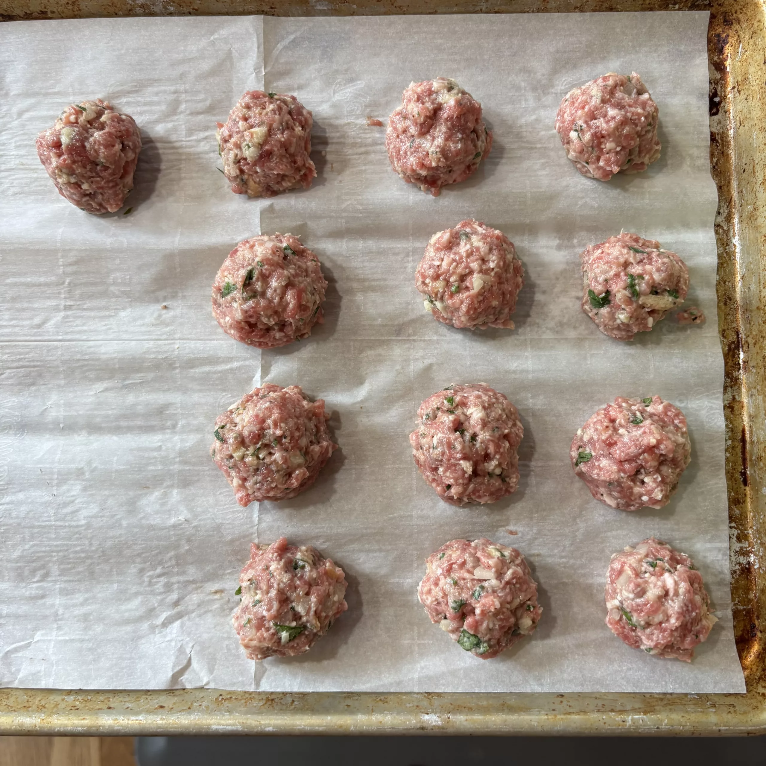 Evenly portioned meatballs on a sheet pan